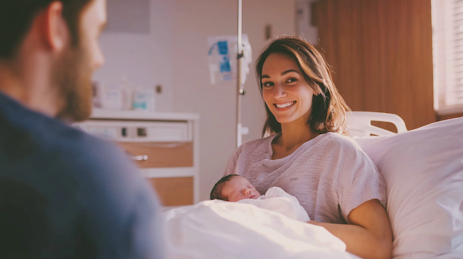 Geplanter Kaiserschnitt Folge 7. Katja sitzt im Bett im Krankenhaus und hält ihr Baby im Arm.